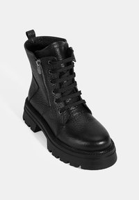 Bottine en cuir noir avec finition texturée, bout rond, avant entièrement lacé et fermeture éclair sur le côté. Semelle épaisse en caoutchouc avec motif de crantage pour une meilleure adhérence.