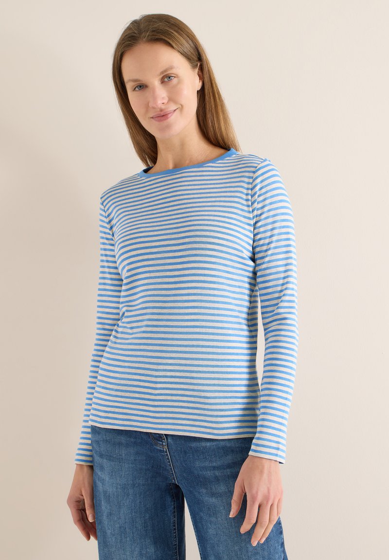 Chemise à manches longues rayée bleu clair et crème, dotée d'un col arrondi et d'un tissu doux et respirant. Portée avec un jean bleu.