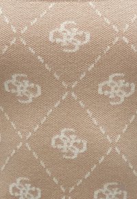 Adīta auduma mīkstā bēšā krāsā ar dimanta rakstu, gaišiem ziedu motīviem un smalku tekstūru visā virsmā.