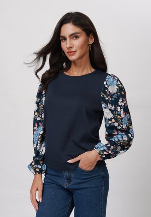 Navy blue top with floral patterned puff sleeves, featuring a round neckline and elastic cuffs, made from a smooth, soft fabric.