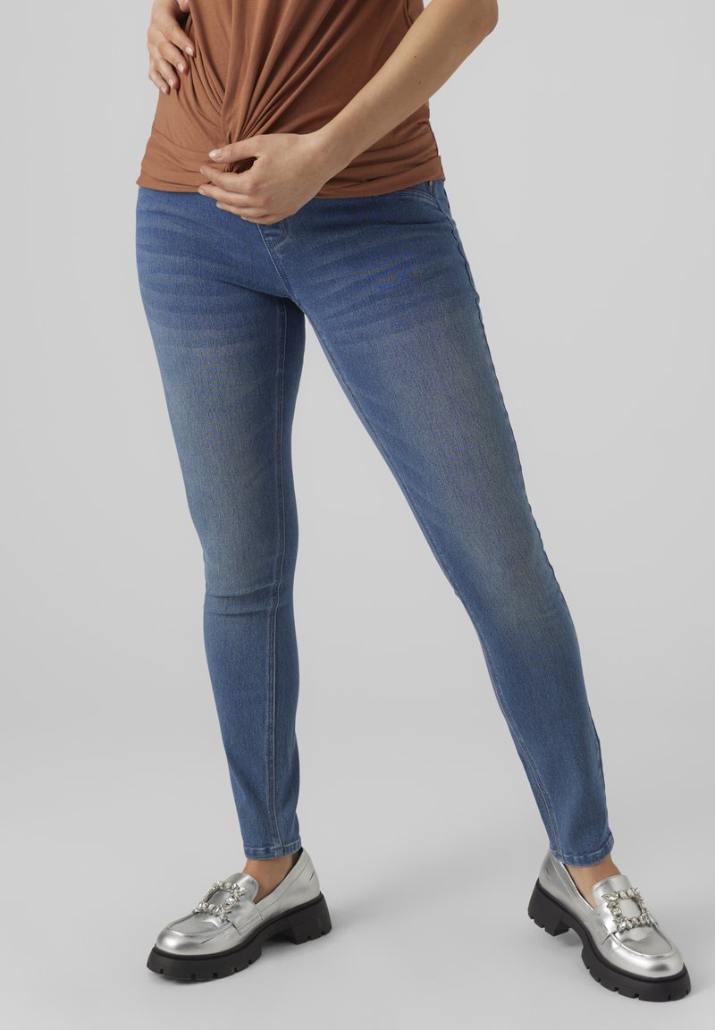 Dunne blauwe jeans met een lichte vervaging, gemaakt van denim. Gecombineerd met metallic zilveren loafers met een decoratieve gesp.