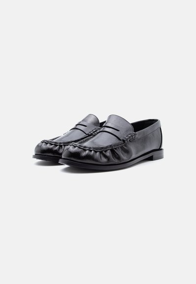 Mocassins noirs en cuir avec coutures au niveau de la partie avant et talon bas, présentés côte à côte sur un fond blanc.