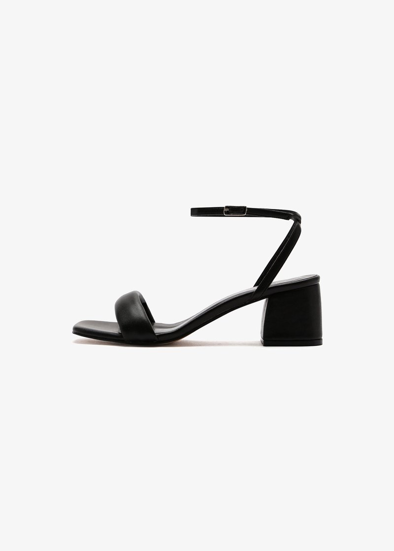Black heeled sandals with a smooth leather upper, featuring a wide strap across the toe and a slim ankle strap. Block heel provides stability.