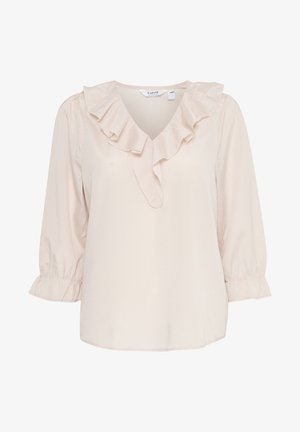 Blouse beige clair avec un décolleté en V, des accents en volants le long du col, et des manches bouffantes trois-quarts avec des manches élastiques. Texture lisse.