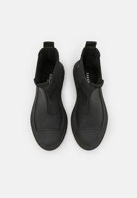 Botas ankle pretas com um design elegante, feitas de couro liso, apresentando painéis laterais elásticos e solas de borracha texturizadas para aderência.