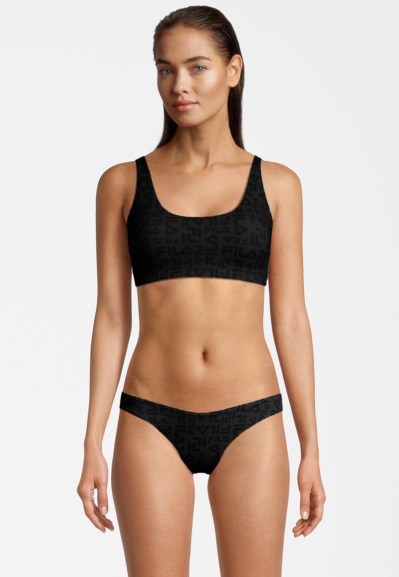 Set bikini nero con top sportivo a scollo rotondo e slip a vita bassa coordinati, entrambi decorati con un motivo a logo in rilievo.
