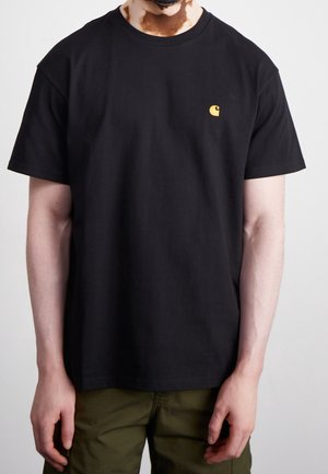 T-shirt en coton noir avec manches courtes et col rond, orné d'un petit logo jaune sur la poitrine.