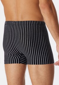 Boxer briefs a righe bianche e nere realizzati in tessuto morbido, con una fascia elastica in vita e un design aderente che si adatta al corpo.