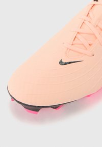 Rožinė futbolo batai su tekstūruota paviršiumi, juodu Nike logotipu ir ryškiai rožinės spalvos kuoleliais. Su raišteliais, suglamžytas dizainas.