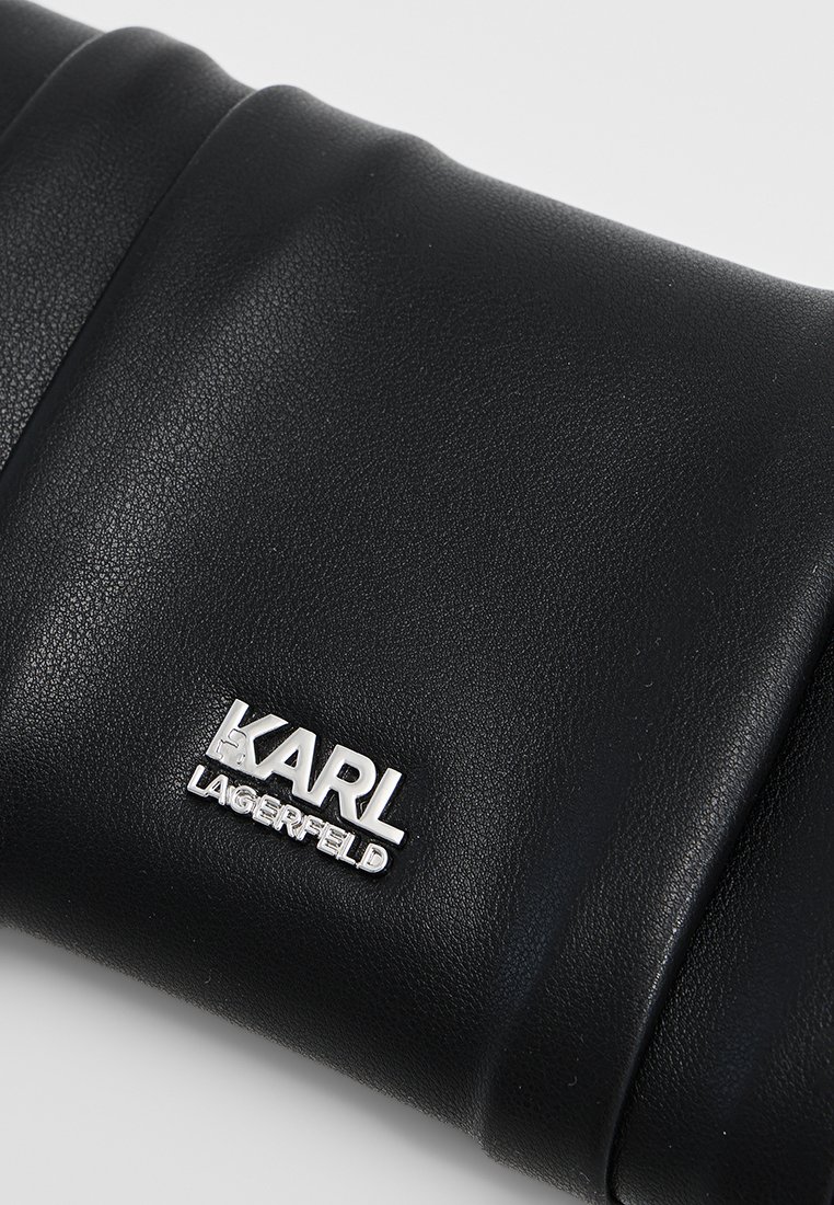 Pochette en cuir noir avec texture matelassée et détails en logo argenté. Elle présente une forme rectangulaire élégante et une finition lisse.
