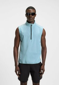 Light blue sleeveless vest with a high collar and black zipper, paired with black shorts. The material appears lightweight and smooth.