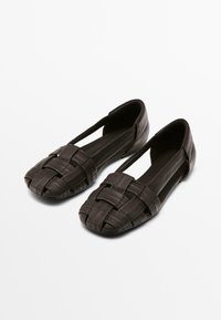 Zwarte geweven platte schoenen van textuurleer, met een open teen en uitsparingsontwerp. Eenvoudige, elegante en lichte structuur.