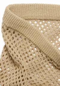 Stickad scarf i beige med öppet vävmönster, som har en texturerad ribbad kant. Materialet verkar mjukt och lättviktigt, vilket gör det lämpligt för lager-på-lager.