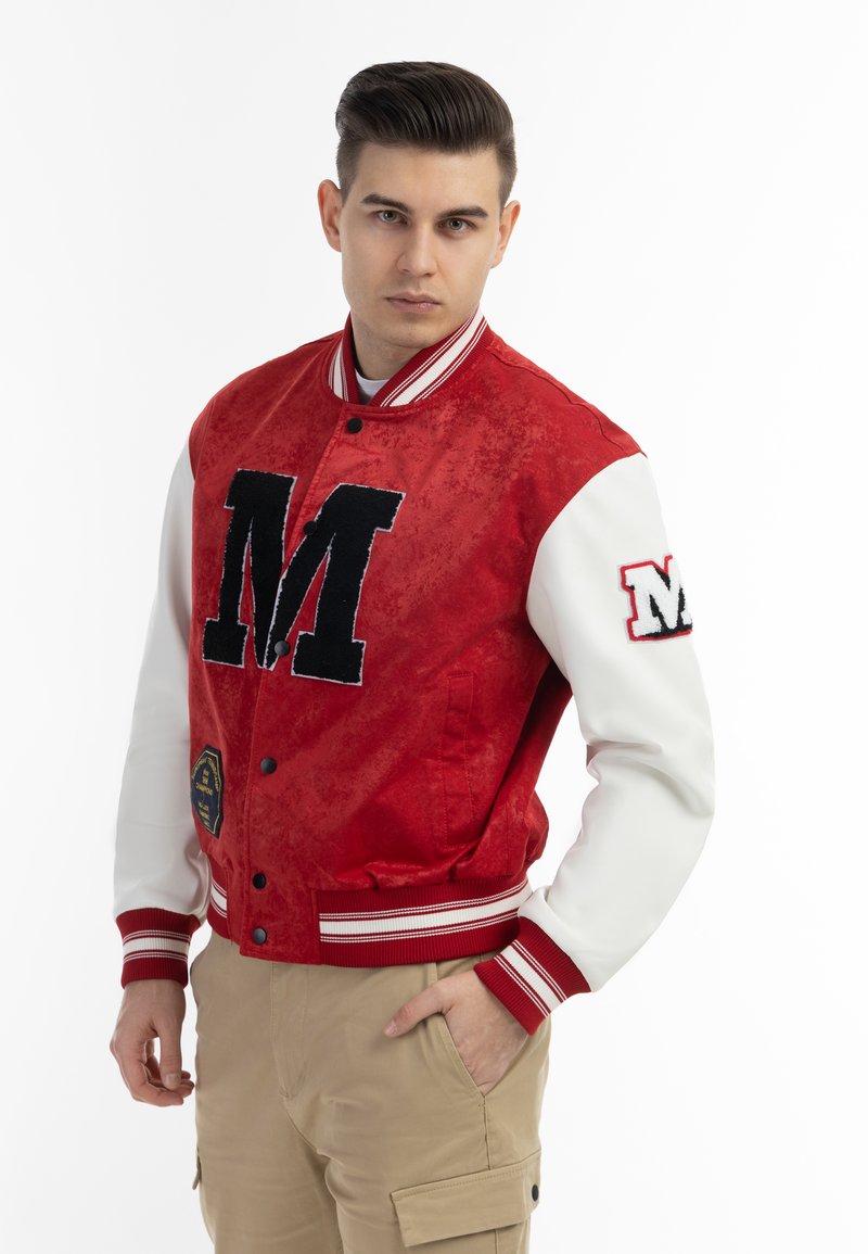 Giacca varsity rossa con corpo testurizzato, maniche bianche, logo "M" nero, colletto e polsini a coste, e tasche laterali. Dettaglio con distintivo dorato sull'orlo.