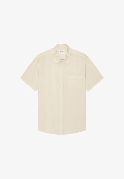 Chemise beige à manches courtes avec boutons, poche poitrine et col classique, étalée à plat sur un fond blanc.