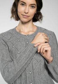 Grau gestrickte Strickjacke mit einem Rautenmuster, Perlenknopf-Akzenten und gerippten Bündchen. Weiche Textur mit taillierter Passform.