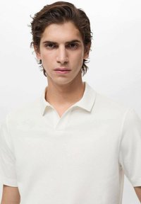 Witte polo met een klassieke kraag, korte mouwen en een gestructureerde stof. Het shirt heeft een aansluitende fit en biedt een minimalistisch ontwerp.