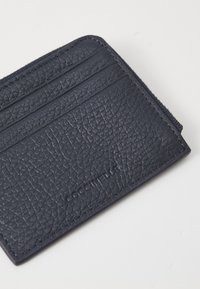 Porta-cartões em pele azul-marinho com textura granulada, múltiplos compartimentos para cartões, fecho com zíper e logótipo da marca em relevo.