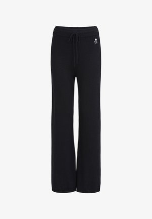 Pantalon large en maille noire avec taille côtelée et cordon de serrage, présentant un petit logo blanc avec un palmier sur la hanche gauche.