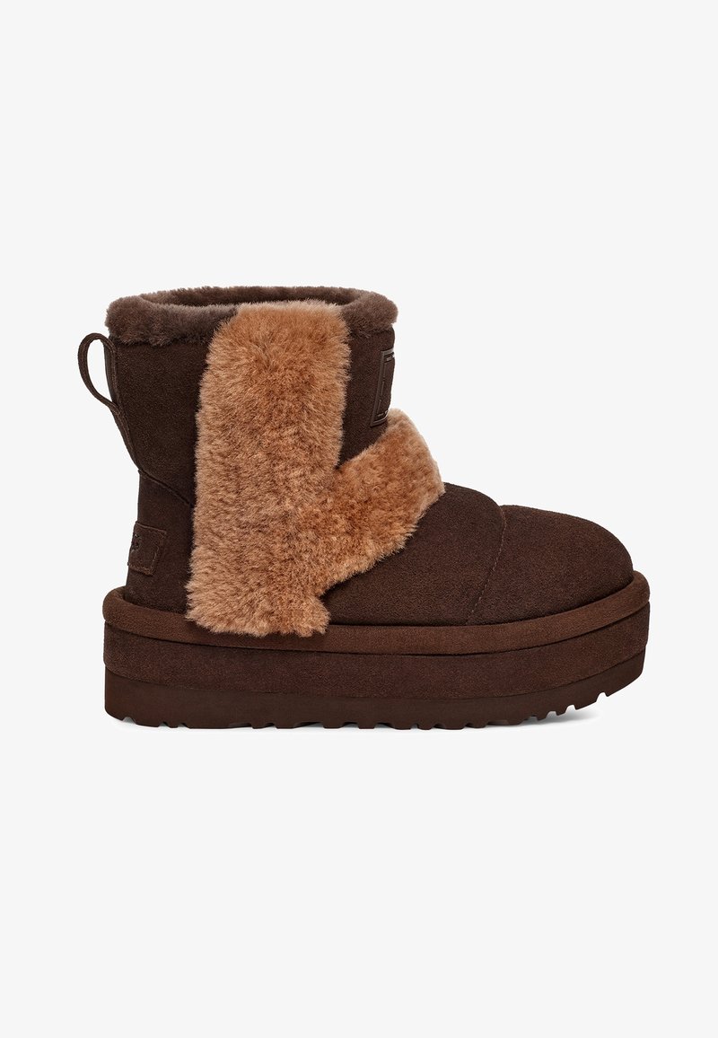Bottine en daim marron avec semelle épaisse en mousse et rabat en shearling beige couvrant l'avant et les côtés sur fond blanc.