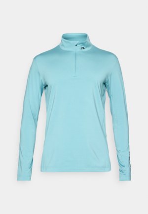 Helles blaues Langarmoberteil mit einem Viertel-Reißverschluss-Kragen, aus glattem Stoff. Verfügt über ein Logo auf der Brust und enganliegende Ärmel mit Nähten.