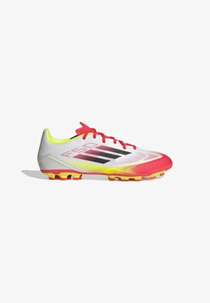 Botas de fútbol blancas y rojas con un upper texturizado, acentos amarillos y un diseño aerodinámico. Presentan un cierre con cordones y tachuelas puntiagudas.