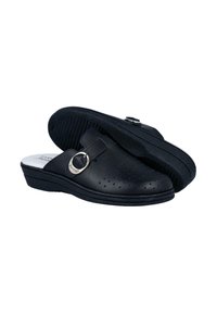 Zuecos de cuero negros con un acento metálico circular, diseño perforado, suela baja en cuña y suela texturizada para mayor agarre.