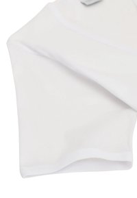 Tessuto bianco con una superficie liscia, caratterizzato da bordi morbidi e una piega. Include un piccolo etichetta in un angolo, che indica dettagli su marca o taglia.