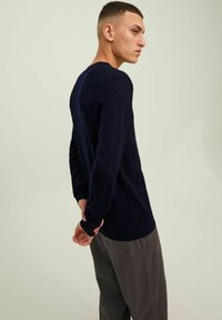 Maglione blu navy a maniche lunghe realizzato in tessuto morbido e testurizzato. Presenta un collo rotondo e polsini a coste con un design aderente.