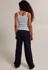 Helles blaues geripptes Tanktop und marineblaue weit geschnittene Hose. Das Outfit hat eine lässige Passform, mit einer Gesäßtasche an der Hose und einer glatten Textur.