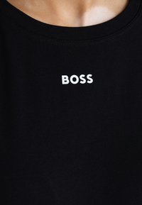Musta puuvillainen t-paita, jossa on pyöreä kaula-aukko. Edessä on valkoinen "BOSS"-logo. Sileä pinta, minimalistinen muotoilu.