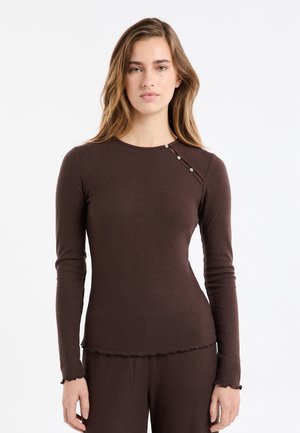 Brązowa prążkowana bluzka z długim rękawem, z okrągłym dekoltem i ozdobnym guzikiem na ramieniu. Dolna krawędź i mankiety wykończone falbanką.
