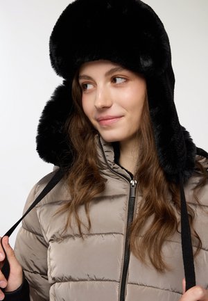 Giubbotto imbottito beige chiaro con cuciture orizzontali, dotato di un cappello in pelliccia sintetica nera. Munito di zip e lacci neri.