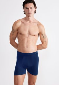 Námořnické modré boxerky vyrobené z měkké tkaniny, s hladkým pasem s logem a těsným střihem pro pohodlí.
