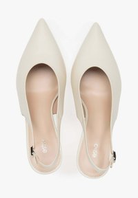 Beige lodičky s špičatou špičkou a otevřenou patou, vyrobené z hladkého, matného materiálu. Mají vystřihovaný design a malou přezku na zapínání kolem kotníku.