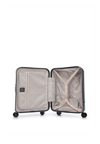 Valise rigide noire ouverte avec intérieur beige, poche zippée en filet d'un côté et sangles croisées réglables de l'autre côté.