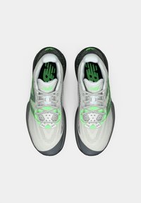 Et par grå og grønne sportssko med reflekterende snørebånd, sort spraglet hæl og grøn branding, vist ovenfra på en hvid baggrund.