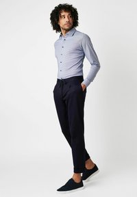 Hemd mit blauer Karomuster, taillierte Passform und langen Ärmeln. Kombiniert mit navy Jogginghosen und dunkelblauen Sneakers.