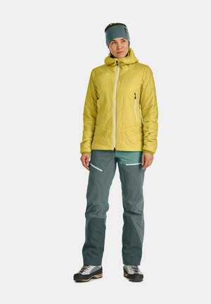 Yellow insulated jacket with zip pockets, paired with gray pants featuring white accents. Accessories include a blue headband.