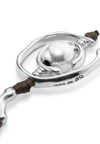 Primer plano de un cierre de pulsera de plata con un centro de perla pulida redonda y cuerdas de cuero marrón a cada lado.