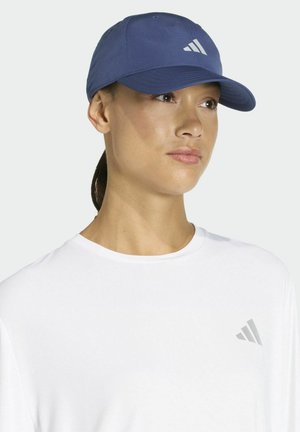 Blauwe honkbalpet met een gebogen rand en een wit logo met drie strepen op de voorkant, gedragen met een wit T-shirt met een bijpassend logo.