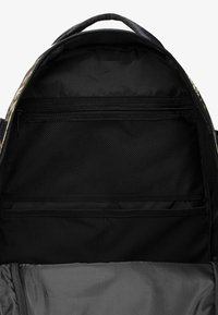 Čierny batoh s vnútrom obsahujúcim zipsovú priehradku a sieťovanú kapsu. Hladká tkaninová podšívka, priestranný dizajn a minimálne hardvérové prvky.