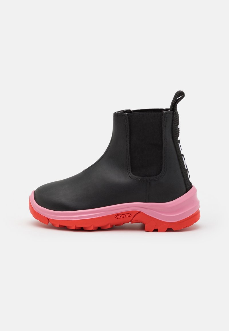Botte Chelsea noire imperméable avec semelle en caoutchouc rose, talon rehaussé et panneaux latéraux élastiques texturés. Elle est dotée d'une languette à l'arrière.