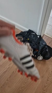 Adidase jalgpallijalats valge pealisega, mustade riba ja oranžide aktsentidega. Omab tekstureeritud disaini ja kummist nuppe haarde saavutamiseks.