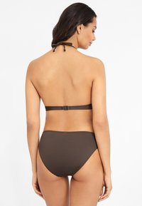Bruin bikini set met een halternek en striksluiting, en een high-waisted onderkant. Soepele textuur, minimalistisch ontwerp, geen patronen.