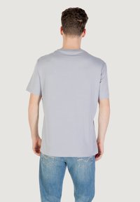 T-shirt grigio chiaro a maniche corte con collo rotondo. Tessuto morbido, vestibilità regolare, superficie liscia e design minimalista.