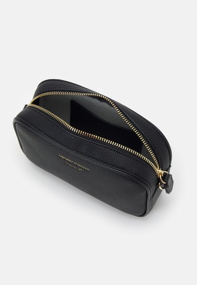 Pochette en cuir noir avec une surface texturée, fermeture éclair dorée et marquage à l'avant. Partiellement ouverte pour montrer l'intérieur.