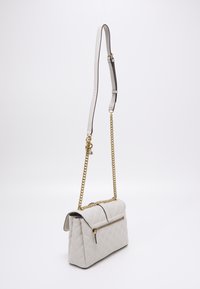 Gequilted witte neplederen handtas met een gouden kettingband en een bovenklep. Bevat een ritssluiting aan de voorkant en een gestructureerd oppervlak.