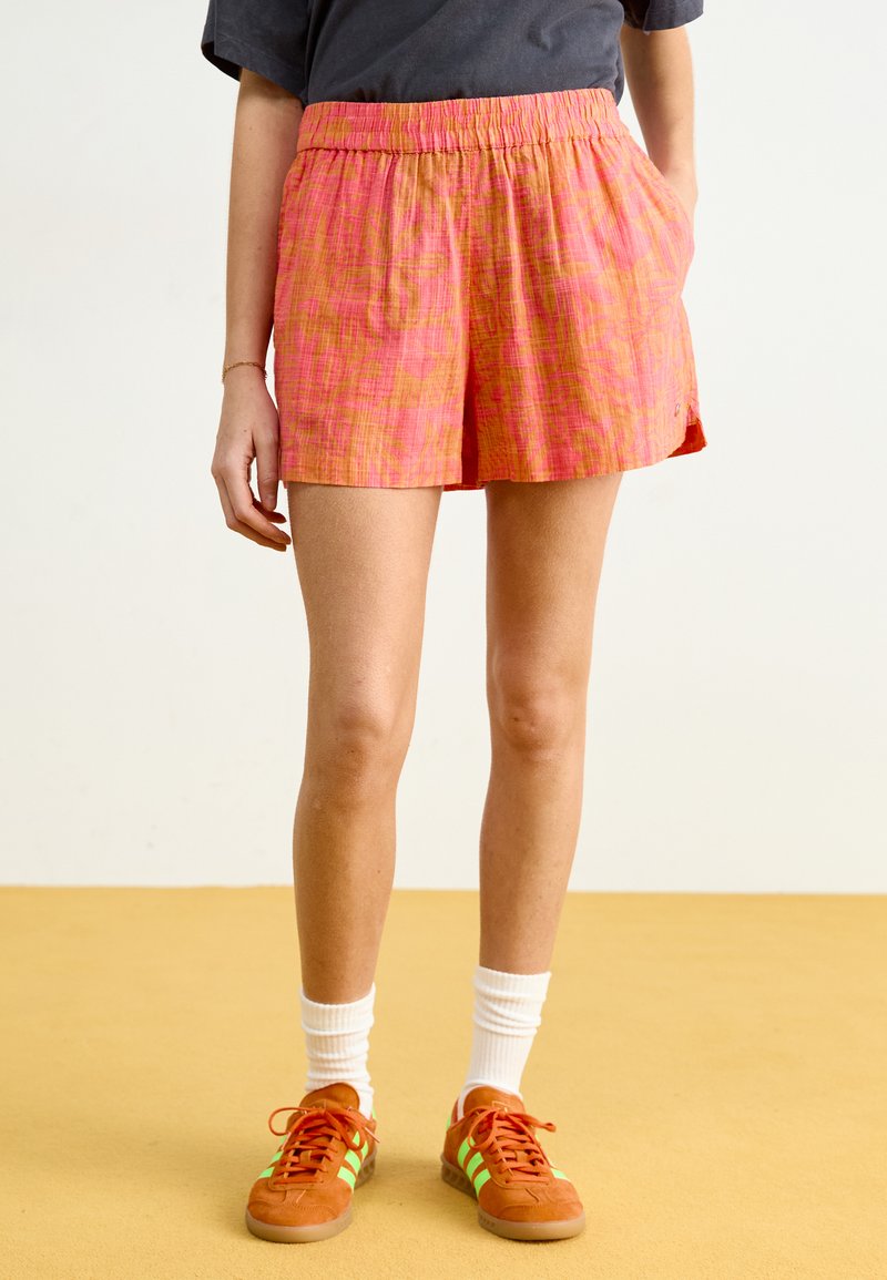 Shorts roses à motif avec une taille élastique et des poches latérales, en tissu léger et d'une coupe légèrement ample.