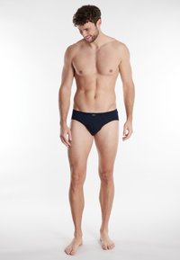 Navyblauwe slips van zachte stof, met een aansluitende pasvorm, smalle tailleband en een minimalistisch ontwerp zonder zichtbare patronen of accenten.